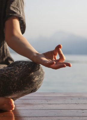 Woman practicing yoga by a lake